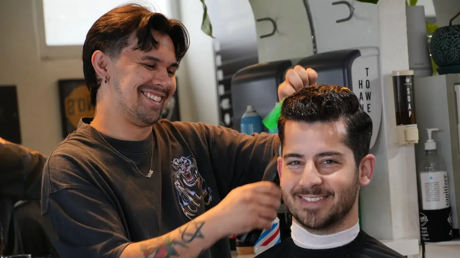 A barber and smiling client during a men's haircut at Dino's Barbershop in Normal Heights, San Diego